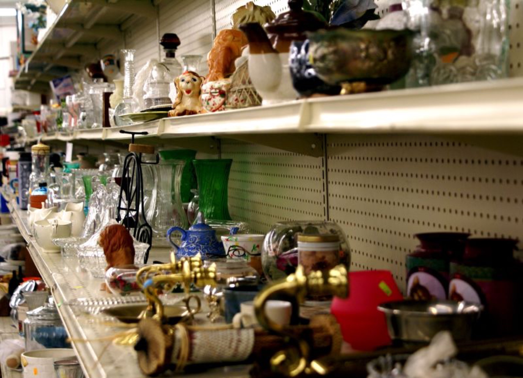 Assorted clothing and household items on thrift store shelves