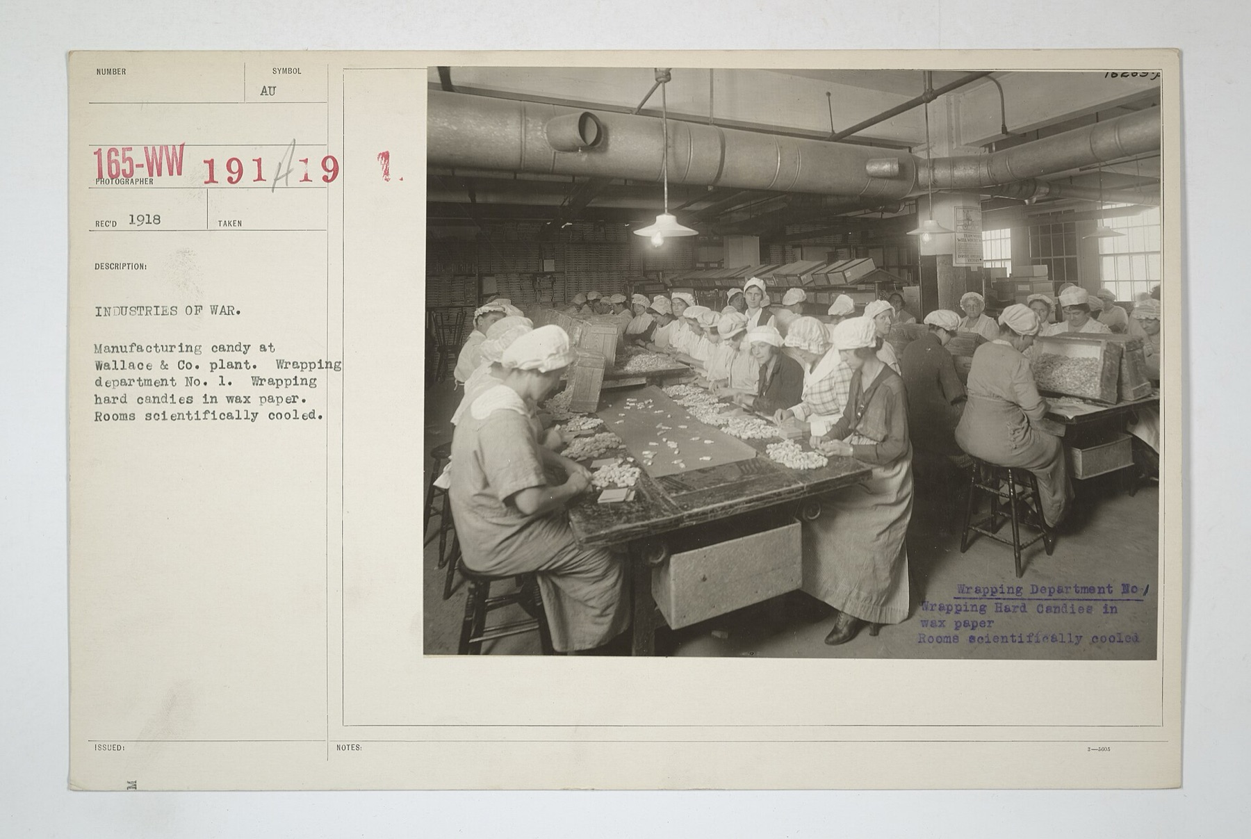 Historic photo of workers wrapping hard candy in wax paper at a factory, illustrating industrial candy wrapping processes.