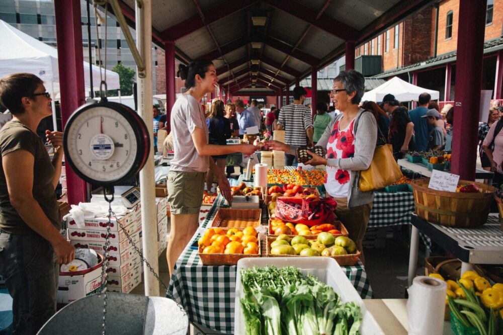 Farmers market stalls with produce displayed in baskets and crates