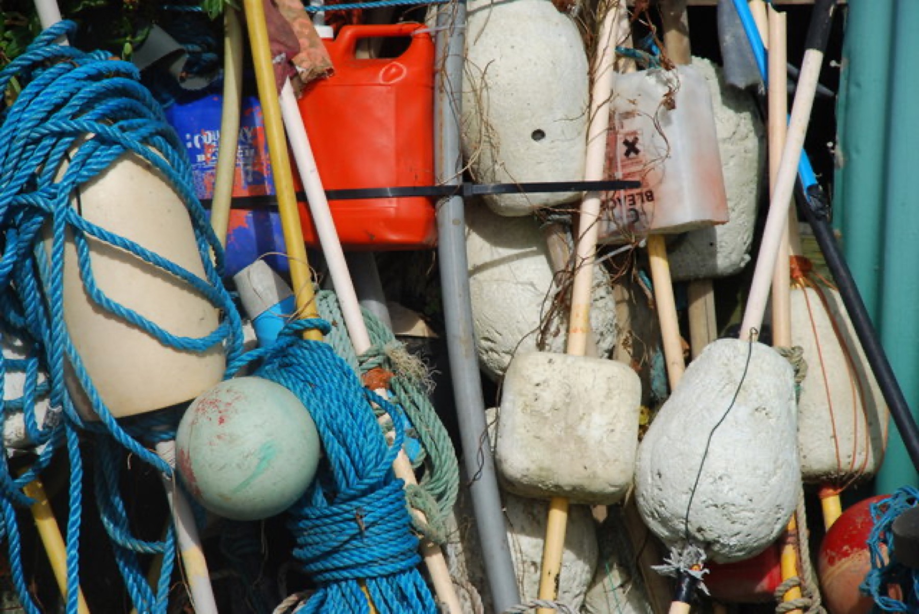 Assorted fishing gear and equipment stacked near a harbor wall