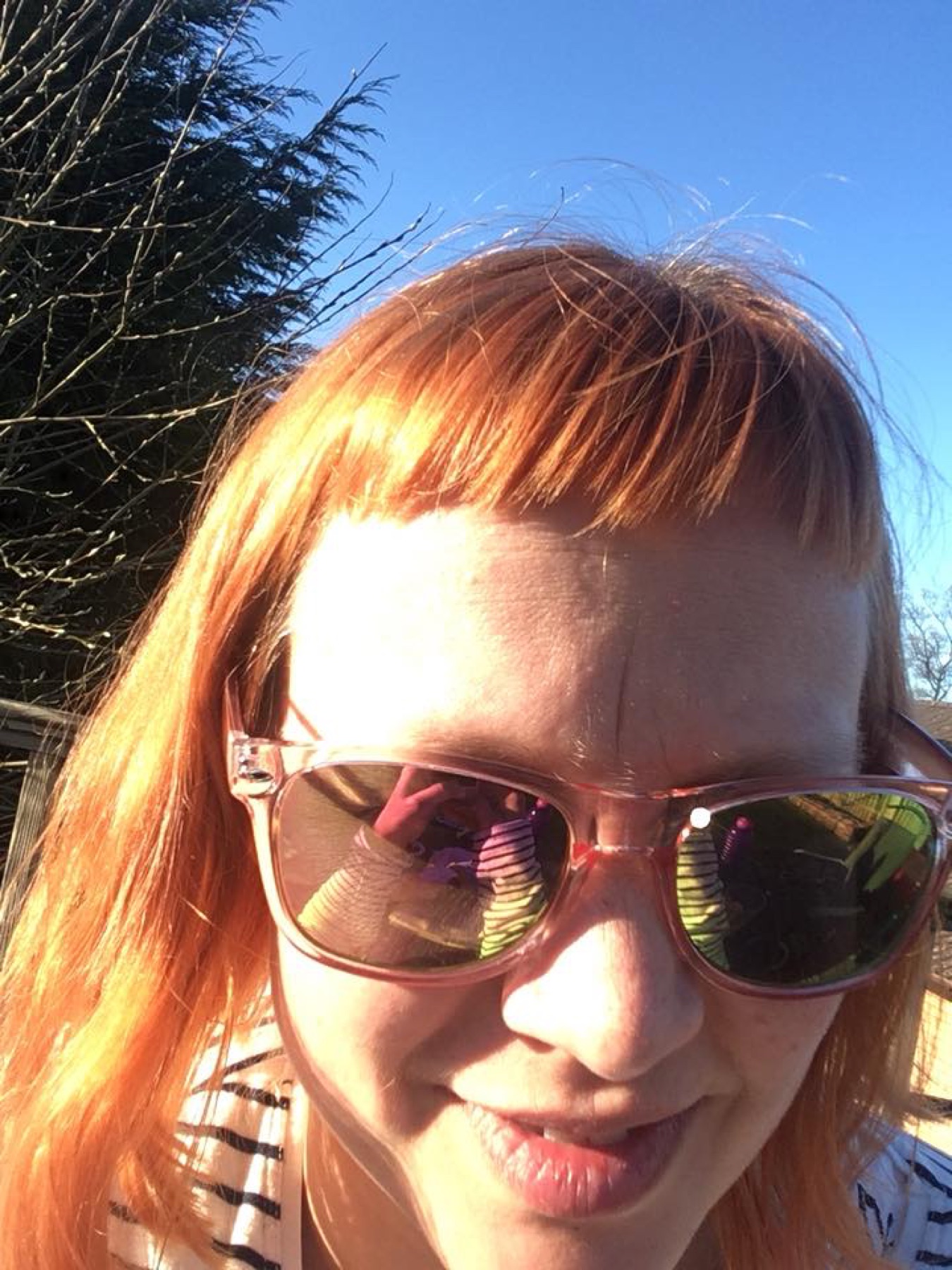 Woman with orange hair and sunglasses wearing bold styling that echoes bright accessory choices