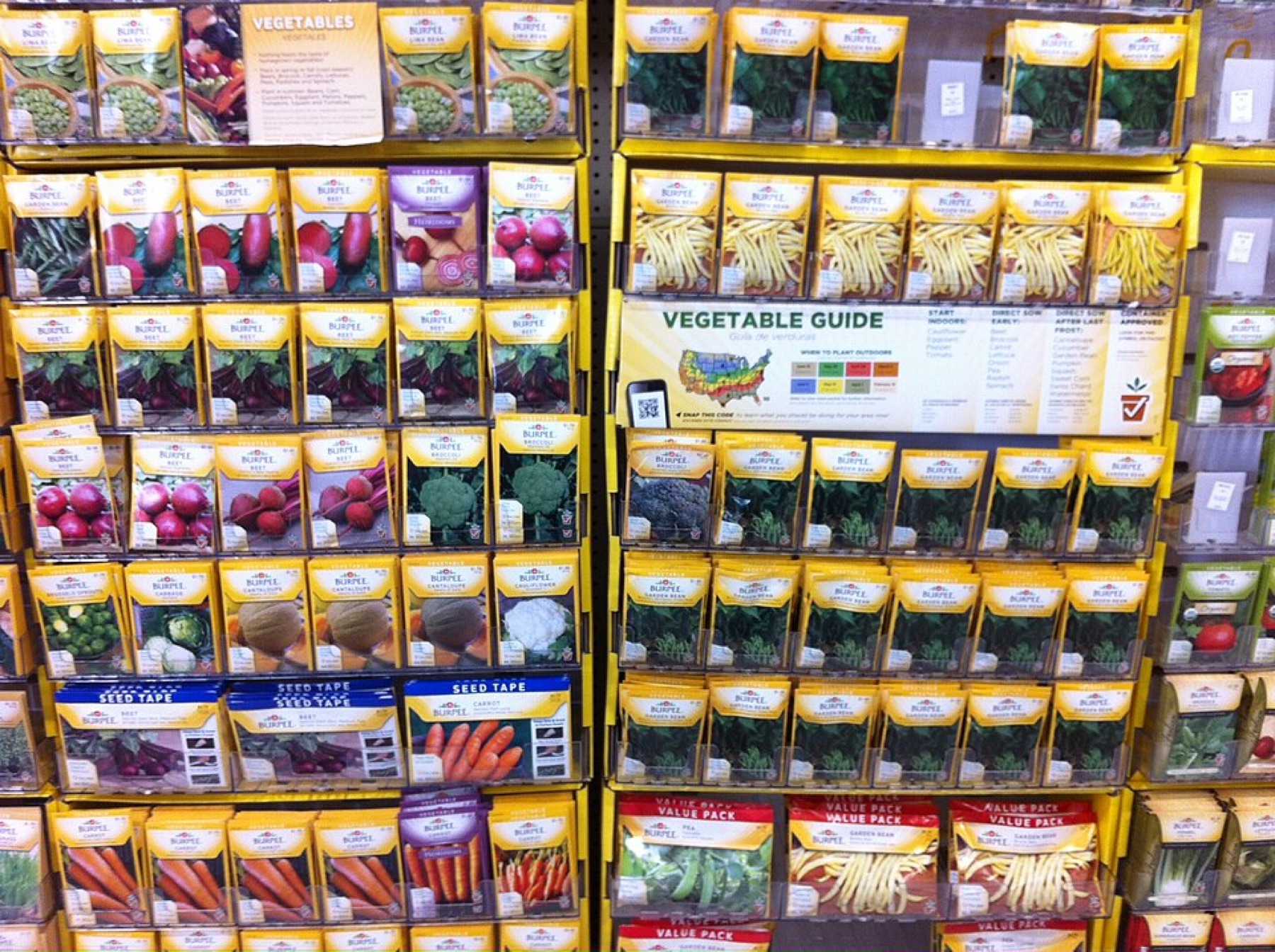 Assorted commercial vegetable seed packets in different designs and sizes laid out on a surface