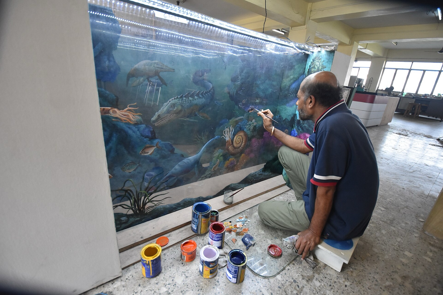 Artist painting on a clear acrylic sheet, illustrating how 1/4" plexiglass works as a durable, transparent surface for creative and display projects.