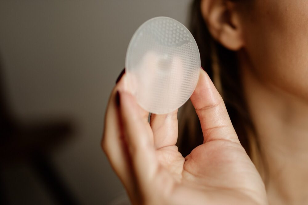 Hand holding a silicone makeup sponge in an indoor setting