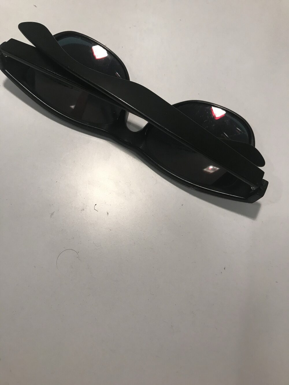 Black sunglasses lying on a white surface