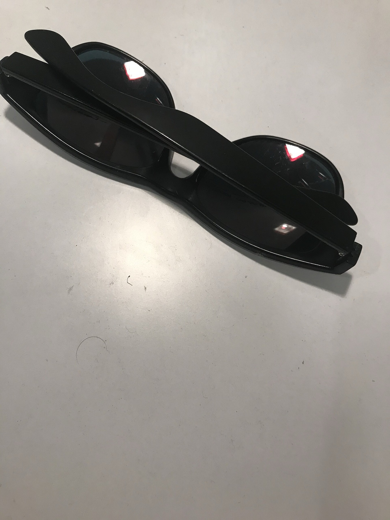 Black sunglasses resting on a white surface