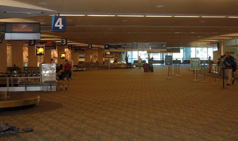Stacked travel bags in an airport claim area, illustrating everyday handbag use