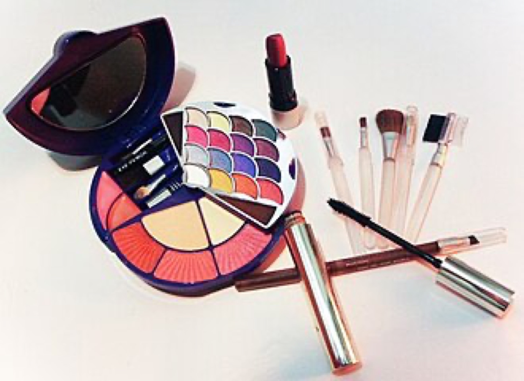 Assorted cosmetics including palettes, brushes, and containers on a table