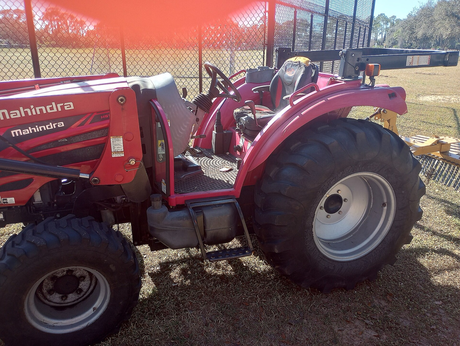 Tracteur Mahindra rouge dans l herbe avec un accessoire arriere