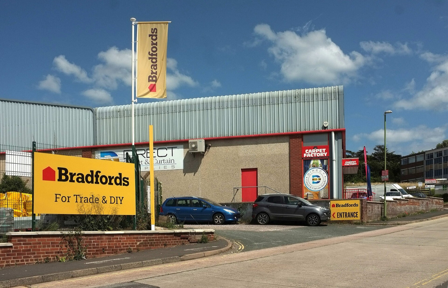 Street view of a building materials supplier with signage and yard