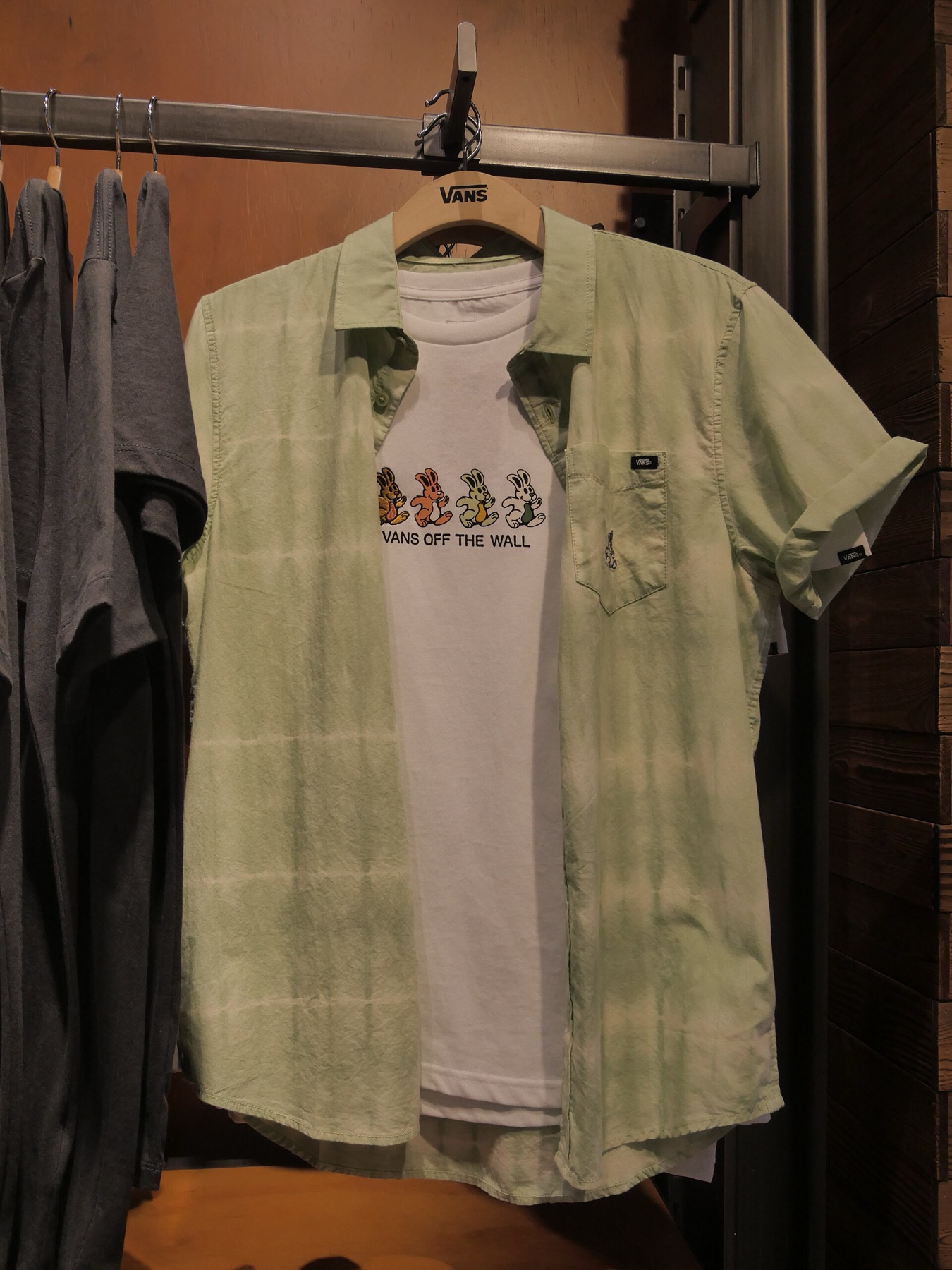 White bunny graphic T‑shirt hanging beside a green patterned shirt