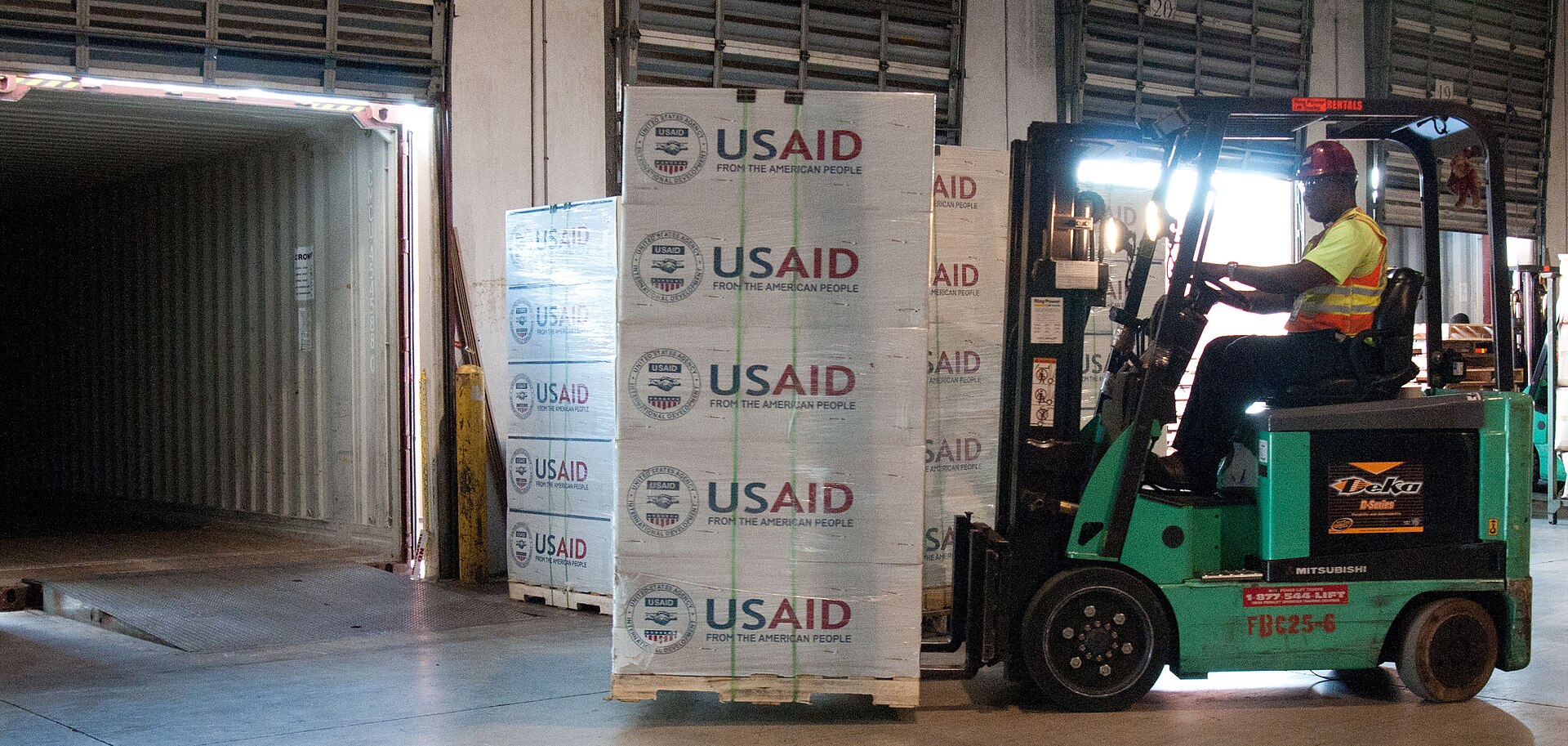 Forklifts moving palletized goods through a large warehouse