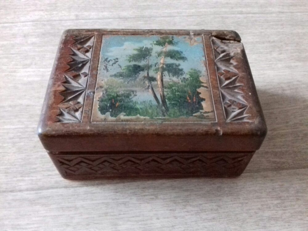 Closed carved wooden jewelry storage box with a painted landscape lid